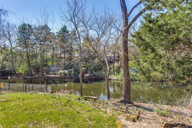 property view of water featuring a wooded view and fence