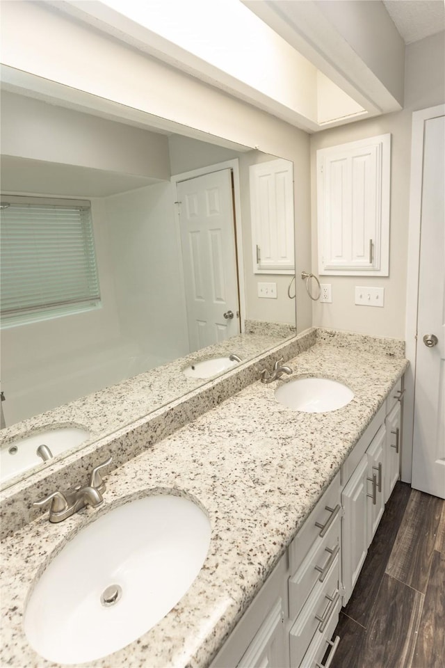 full bath with a sink, wood finished floors, and double vanity