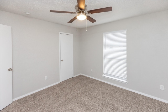 empty room with a ceiling fan, carpet, baseboards, and a textured ceiling