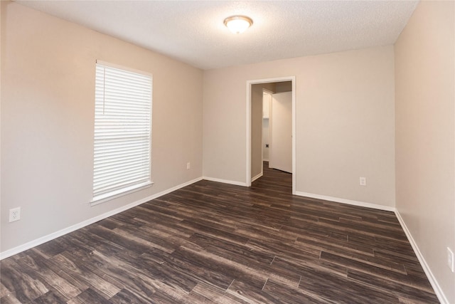 spare room featuring baseboards, a textured ceiling, and dark wood-style floors