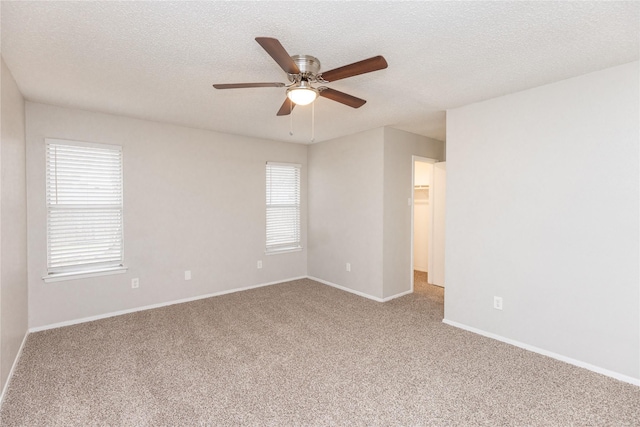 carpeted empty room with baseboards, a textured ceiling, and ceiling fan