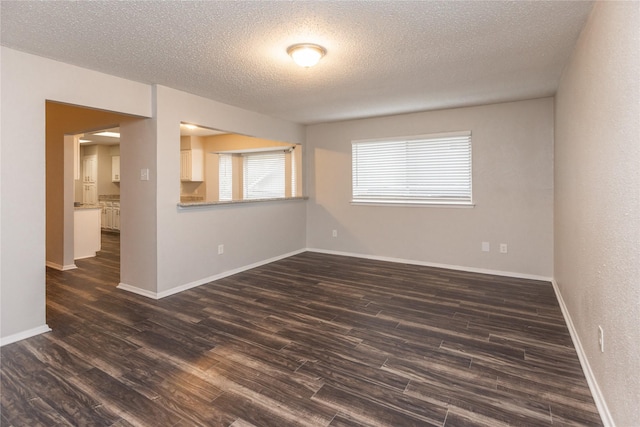 empty room featuring baseboards, dark wood-style flooring, and a textured ceiling