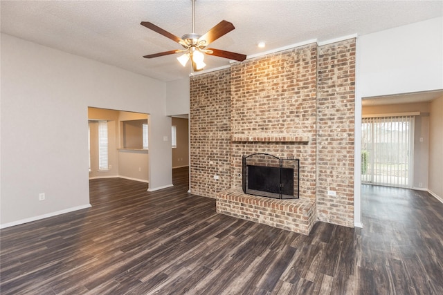 unfurnished living room with a ceiling fan, a textured ceiling, wood finished floors, baseboards, and a brick fireplace