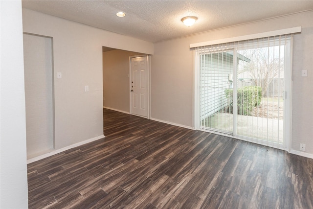 unfurnished room with dark wood-type flooring, baseboards, and a textured ceiling