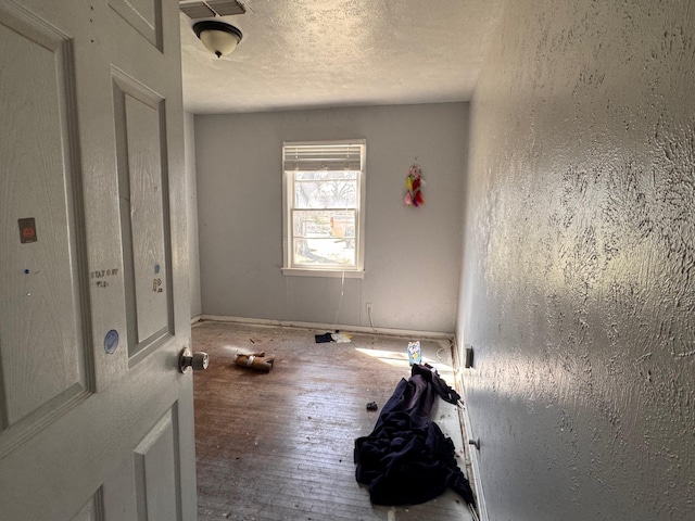 interior space featuring visible vents, a textured ceiling, and hardwood / wood-style floors