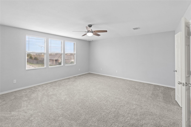 carpeted empty room with visible vents, baseboards, and ceiling fan