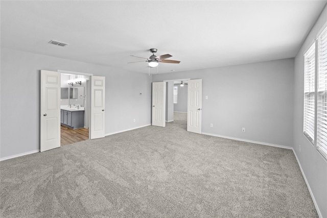 unfurnished bedroom featuring visible vents, baseboards, carpet floors, ensuite bathroom, and a sink