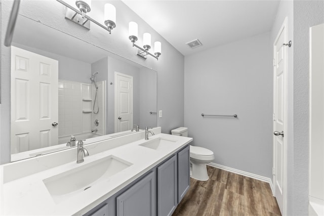 full bath featuring toilet, wood finished floors, visible vents, and a sink