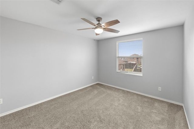 carpeted spare room featuring a ceiling fan and baseboards