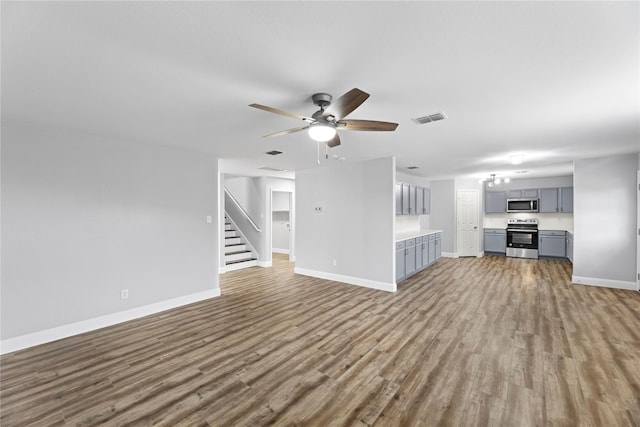 unfurnished living room featuring visible vents, baseboards, a ceiling fan, and wood finished floors