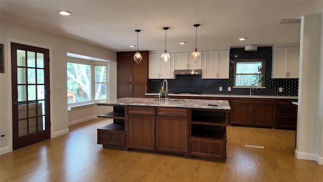 kitchen with open shelves, a sink, light wood-style floors, white cabinets, and decorative backsplash