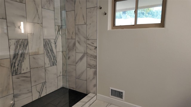 bathroom featuring visible vents and a tile shower