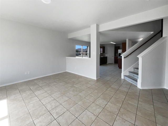 unfurnished living room with light tile patterned floors, baseboards, and stairs