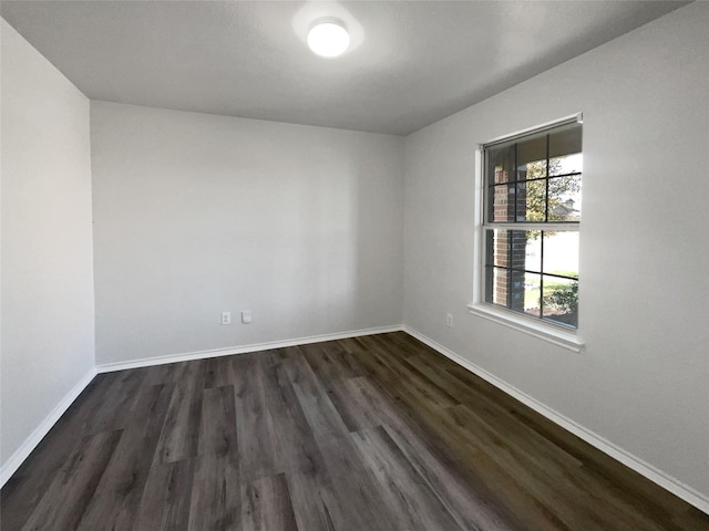 spare room featuring dark wood-style floors and baseboards