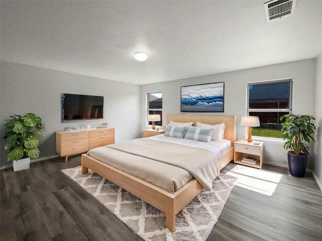 bedroom with visible vents, baseboards, and dark wood-type flooring