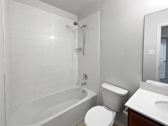 bathroom with toilet, vanity, a textured wall, and washtub / shower combination