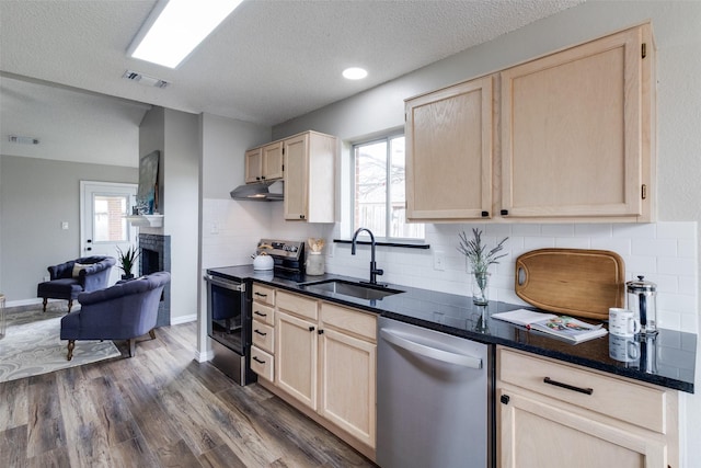 kitchen with light brown cabinets, appliances with stainless steel finishes, under cabinet range hood, and a sink