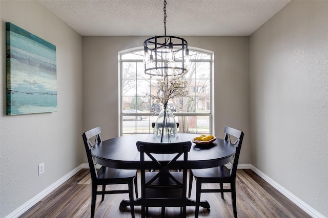 dining room with a chandelier, a textured ceiling, baseboards, and dark wood-style flooring