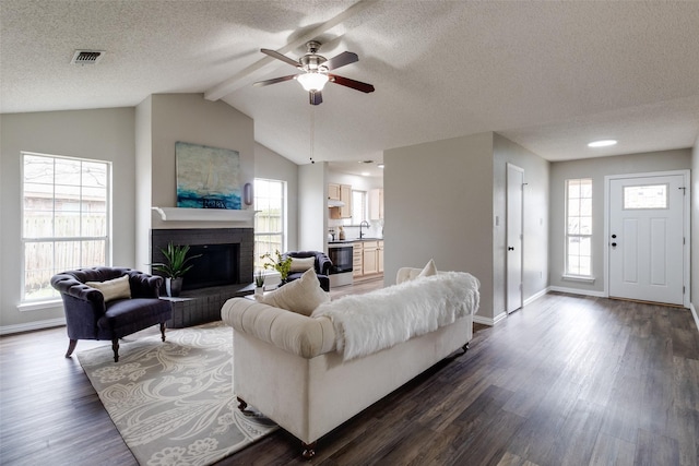 living room featuring visible vents, a brick fireplace, vaulted ceiling with beams, dark wood-type flooring, and baseboards