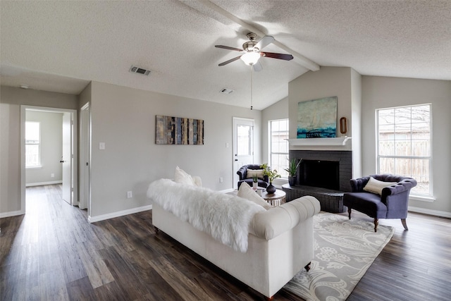 living room featuring lofted ceiling with beams, visible vents, plenty of natural light, and dark wood-style floors