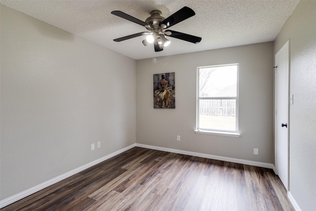 empty room featuring baseboards, dark wood-type flooring, a ceiling fan, and a textured ceiling