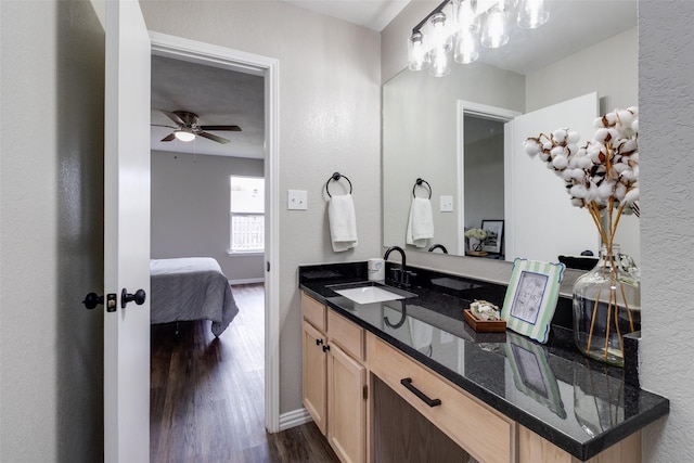 bathroom with a ceiling fan, wood finished floors, connected bathroom, baseboards, and vanity