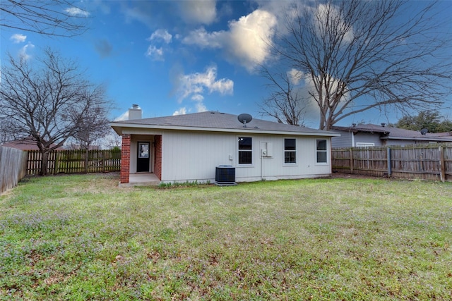 rear view of house with a fenced backyard, a chimney, and a yard