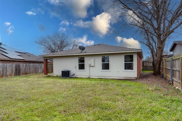 rear view of property featuring central AC unit, a lawn, and a fenced backyard