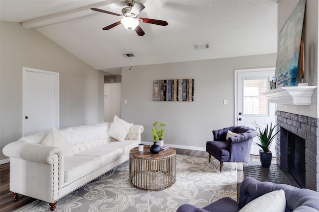 living room with visible vents, wood finished floors, a fireplace, baseboards, and vaulted ceiling with beams