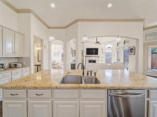 kitchen with a tiled fireplace, open floor plan, dishwasher, decorative backsplash, and a sink