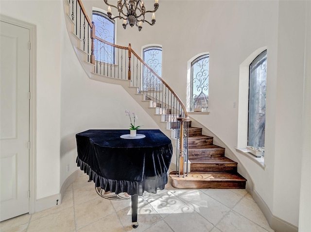 entryway featuring a chandelier, a high ceiling, stairs, and baseboards