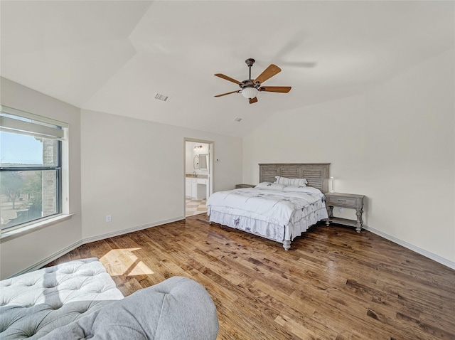 bedroom with visible vents, wood finished floors, baseboards, and vaulted ceiling