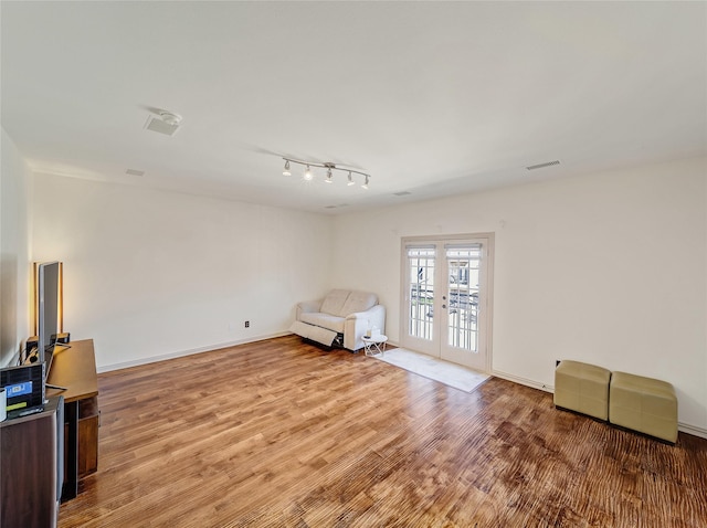 living area featuring french doors, baseboards, light wood-style floors, and visible vents