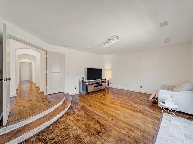 living room with visible vents, wood finished floors, arched walkways, and baseboards