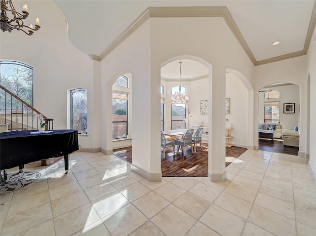 foyer entrance with crown molding, light tile patterned floors, a towering ceiling, and a chandelier