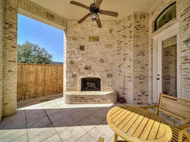 view of patio / terrace with an outdoor stone fireplace, a ceiling fan, and fence