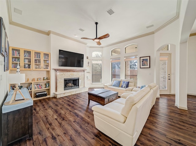 living area featuring a high end fireplace, visible vents, dark wood-type flooring, and ceiling fan