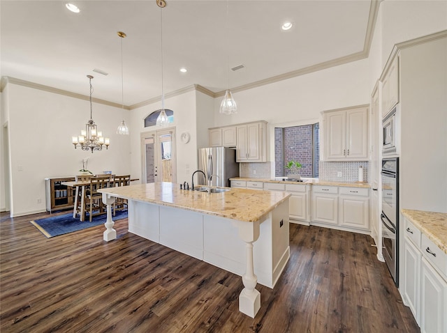 kitchen with a center island with sink, dark wood-style flooring, a sink, decorative backsplash, and stainless steel appliances