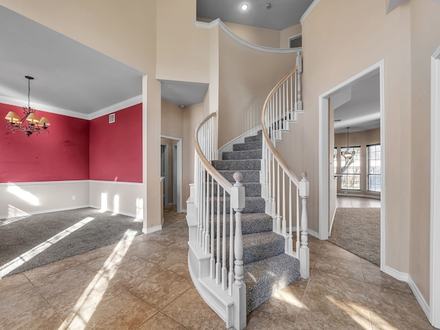 stairway featuring baseboards, a notable chandelier, and a high ceiling