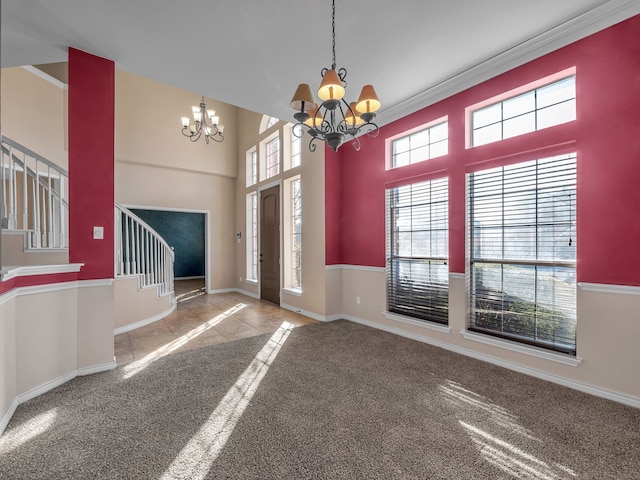 carpeted foyer entrance with baseboards, a notable chandelier, a towering ceiling, and stairs