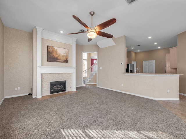 unfurnished living room with baseboards, ceiling fan, carpet floors, recessed lighting, and a tile fireplace