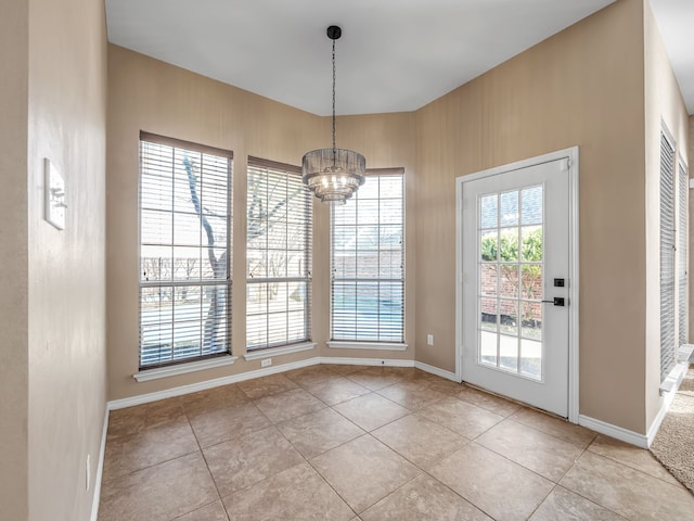 unfurnished dining area with a chandelier, light tile patterned floors, and baseboards