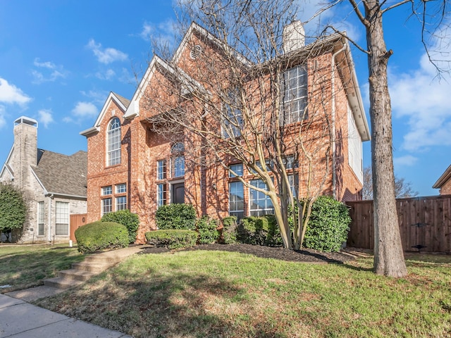 traditional-style house featuring a front yard, fence, brick siding, and a chimney