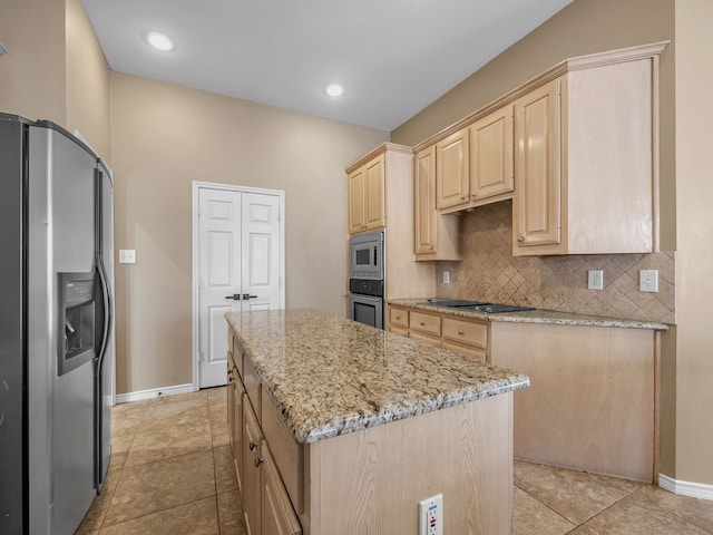 kitchen featuring a center island, light stone countertops, light brown cabinetry, decorative backsplash, and appliances with stainless steel finishes