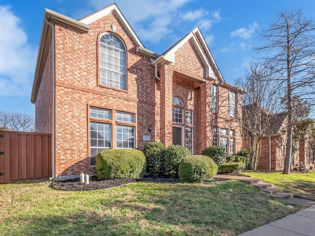 view of front of house with a front yard, fence, and brick siding