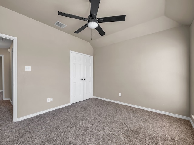 unfurnished bedroom featuring visible vents, dark carpet, a closet, baseboards, and vaulted ceiling