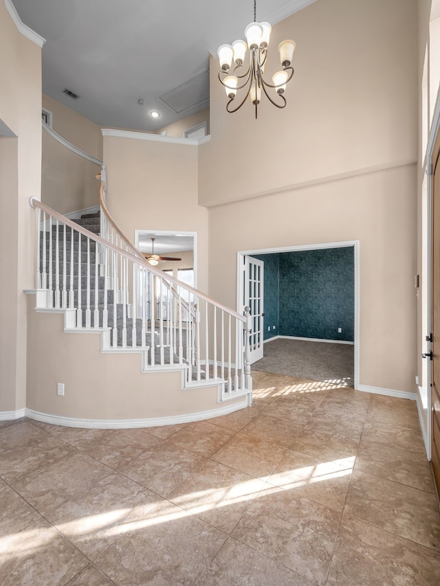 entrance foyer featuring visible vents, ceiling fan with notable chandelier, stairway, baseboards, and a towering ceiling