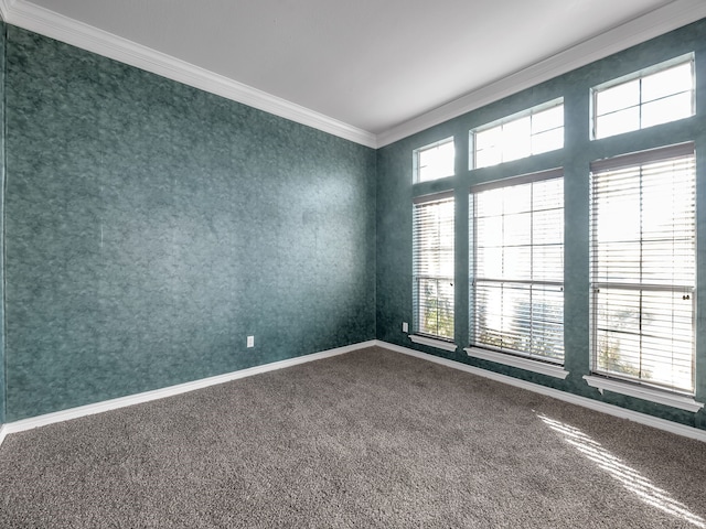 empty room with a wealth of natural light, dark carpet, baseboards, and ornamental molding