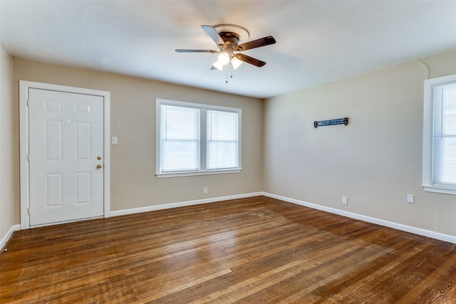 empty room featuring baseboards, a ceiling fan, and dark wood-style flooring