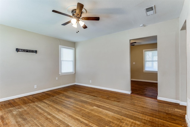 spare room with wood finished floors, visible vents, a wealth of natural light, and baseboards